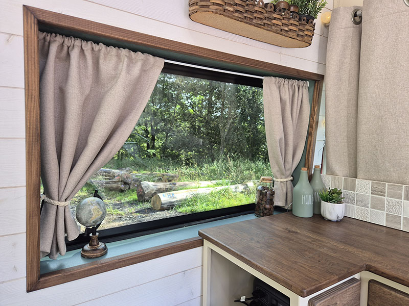 Aménagement de van sur mesure par Cosy Van à Strasbourg : fenêtre installée avec rideaux isolants sur Peugeot Boxer, plan de travail en bois massif pensé pour la vie en van