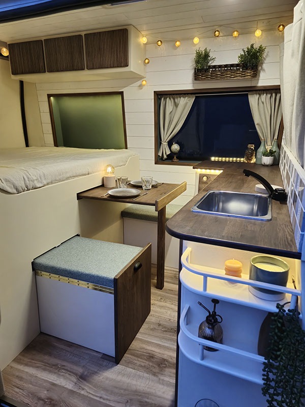 Intérieur d'un van Peugeot Boxer entièrement aménagé avec cuisine, espace de couchage et rangements, idéal pour la vie nomade en Alsace et partout en France. Explorez des aménagements de van sur mesure avec Cosy Van à Strasbourg.