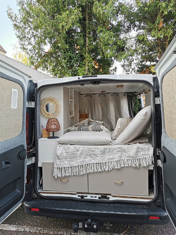 Vue arrière d'un Renault Trafic en van aménagé avec des rangements sous le lit et un coin couchage pour deux personnes pour des voyages en Alsace et dans toute la France