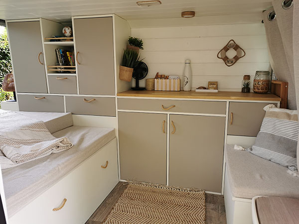 Vue intérieure d'un van aménagé par Cosy Van avec des finitions artisanales en bois massif dans un Renault Trafic III.
