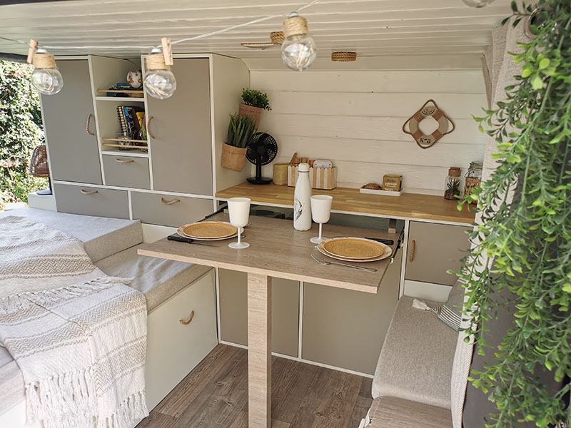 Vue intérieure d'un van aménagé sur mesure par Cosy van à Strasbourg. Van avec un coin salon convertible en lit ou en coin cuisine avec une table escamotable.